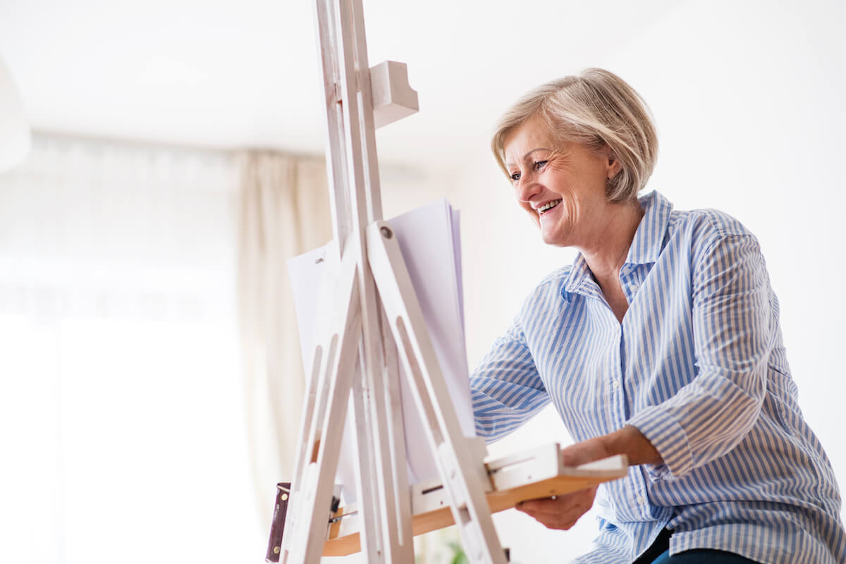 A senior woman painting at home