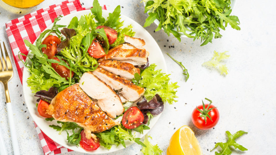 Grilled chicken with green salad. Keto diet, healthy eating. Top view on white table with space for text.