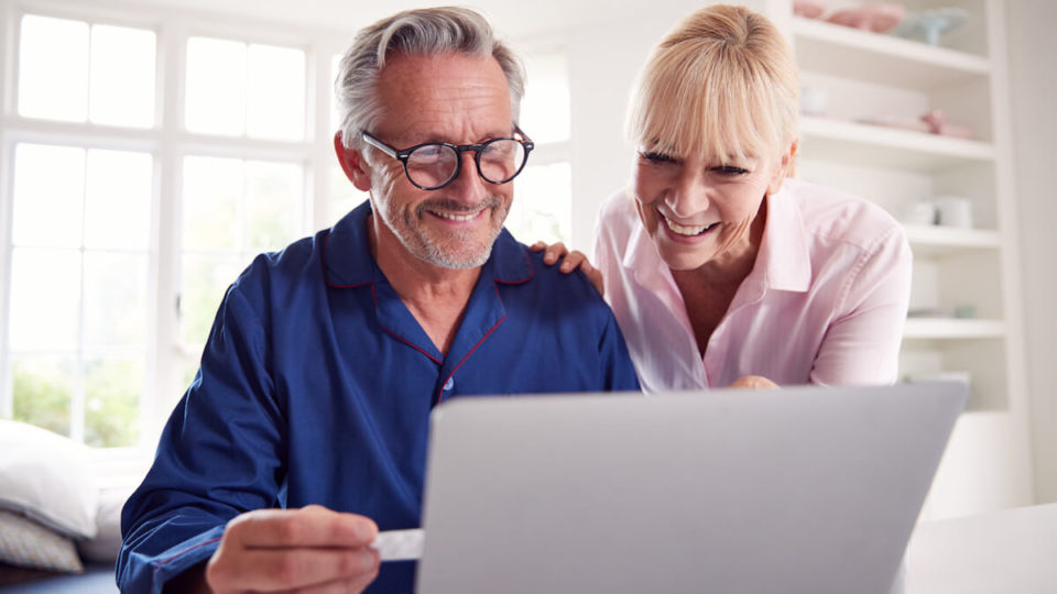 Mature Couple At Home Looking Up Information Online Using Laptop