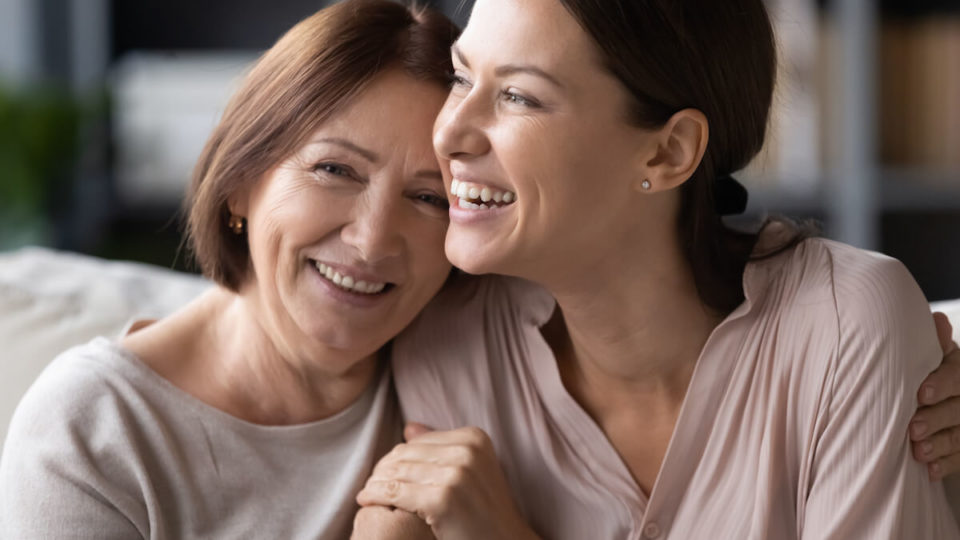 Close up head shot portrait smiling mature mother and grownup daughter cuddling,