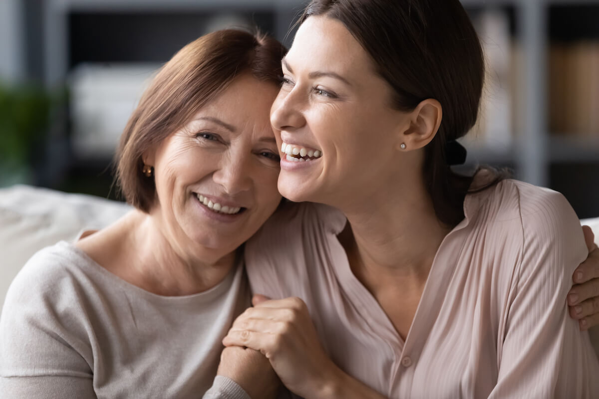 Close up head shot portrait smiling mature mother and grownup daughter cuddling,