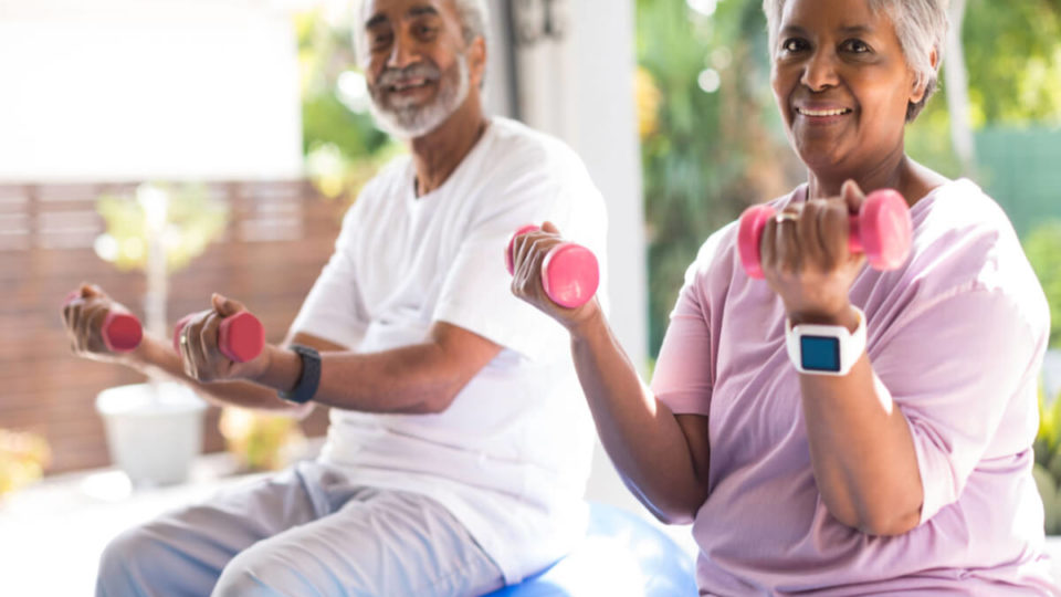 Older Couple Lifting Light Weights, Sitting on Exercise Balls