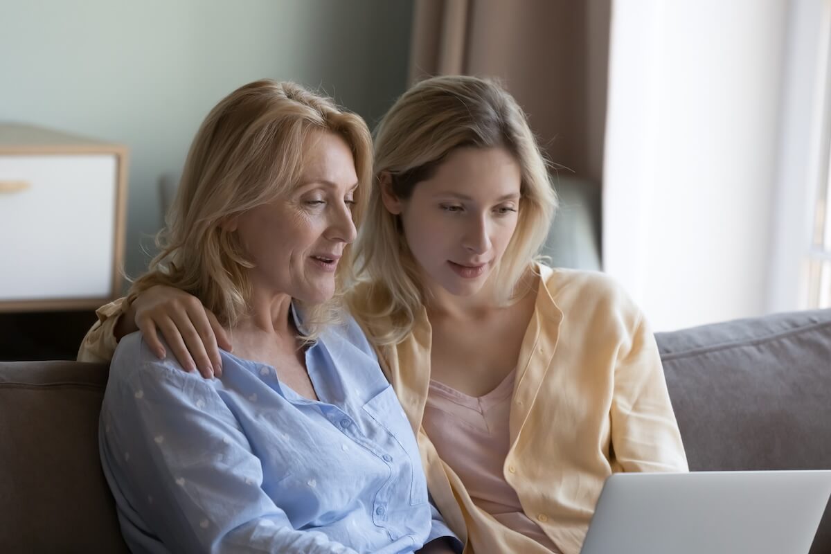 Focused positive mature mother and beautiful young grownup daughter using online ecommerce app on laptop, watching movie, interactive TV channel, enjoying domestic wireless connection, communication What if Mom Doesn’t Want to Move to Senior Living