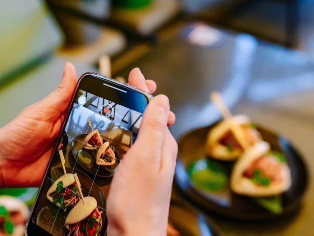 Hand with smartphone photographing food