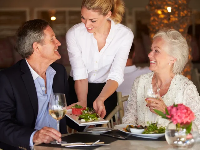 Waitress Serving Food To Senior Couple